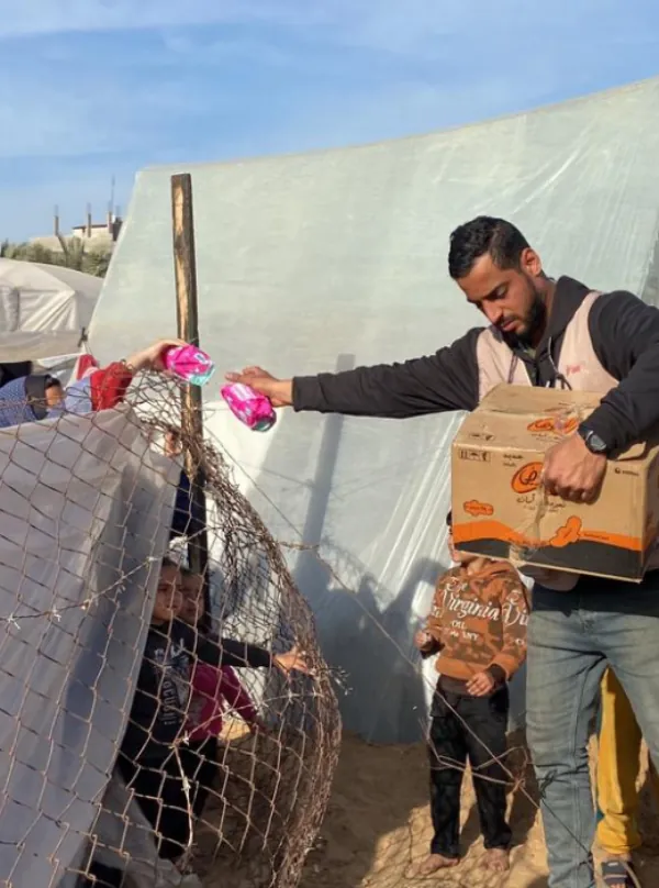 Umma Relief volunteer distributing essential sanitary products to a woman in Gaza, supporting health and hygiene in conflict zones.
