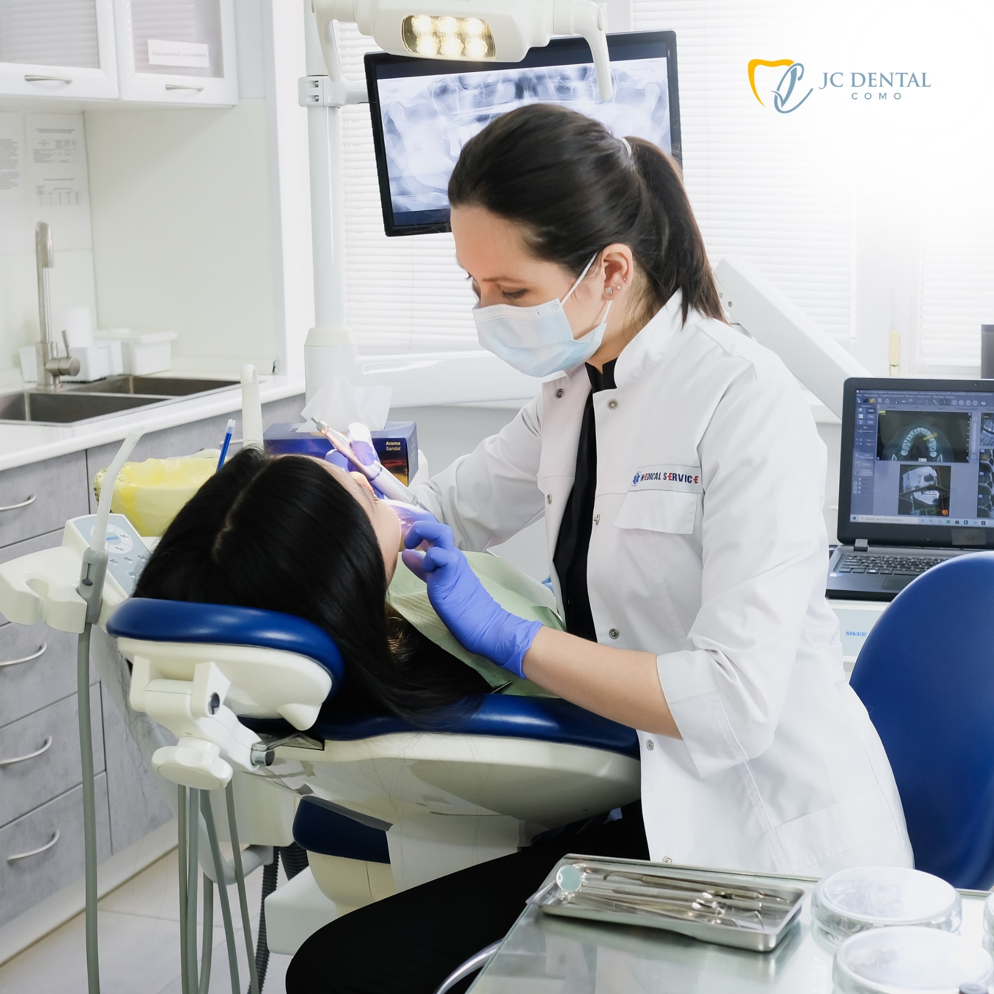 A professional dentist performing a wisdom teeth removal procedure on a patient in a modern surgical suite - JC Dental Como