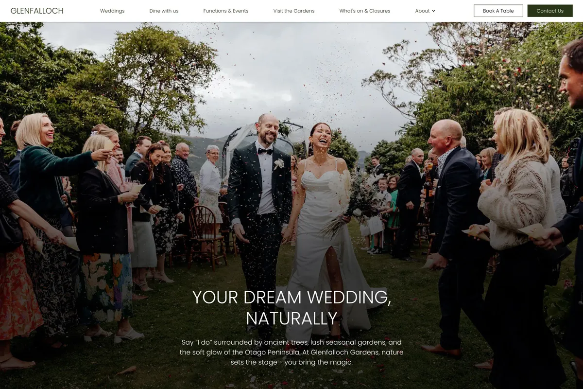 Newlywed couple smiling and holding hands while guests throw confetti in an outdoor garden wedding ceremony.