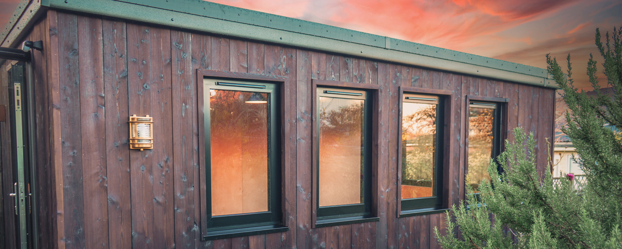 Luxury bespoke garden room with warm lighting and outdoor decking at dusk