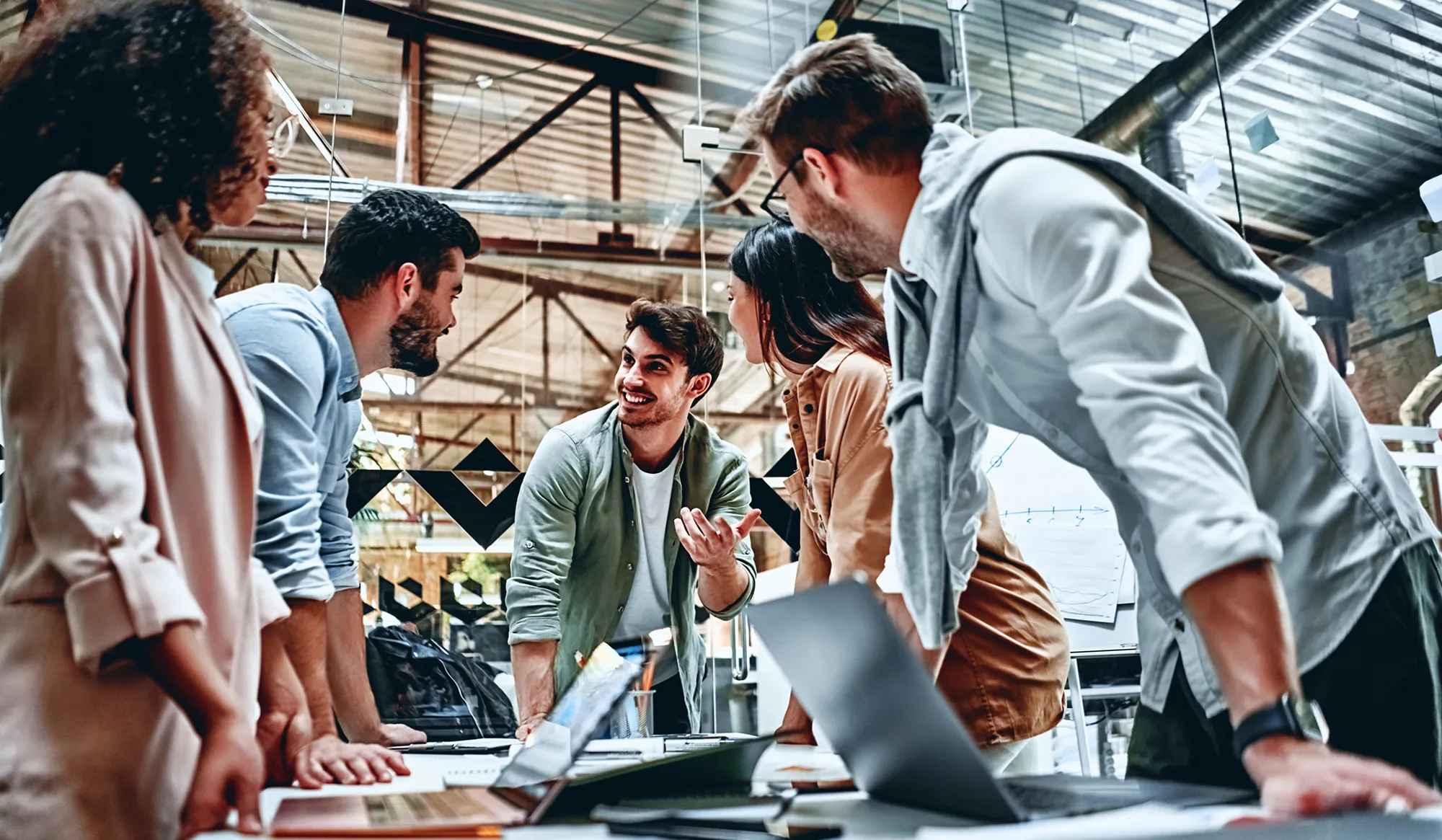 Business team discussing plans around a laptop in an open-plan office