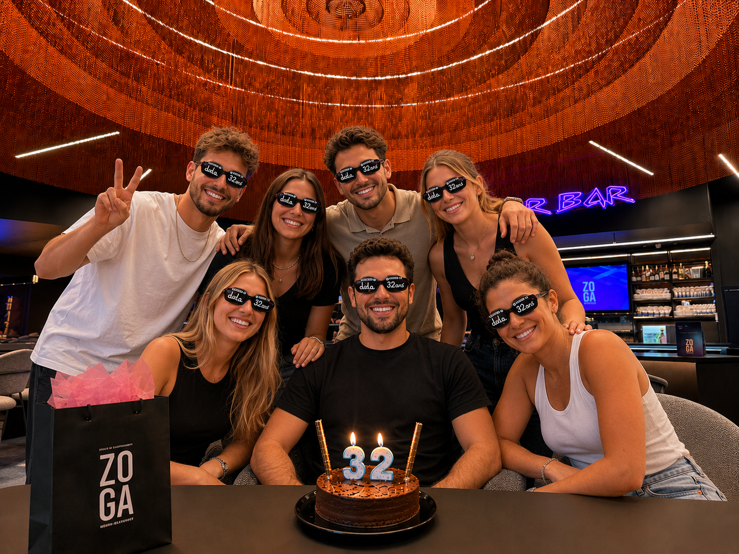 Groupe de jeunes adultes autour d’un gâteau d’anniversaire avec lunettes ZOGA