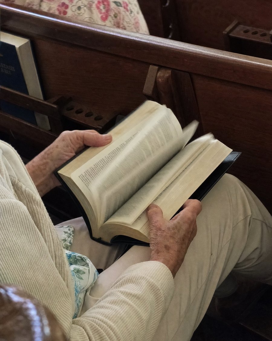 Hands flipping through a Bible with no tabs during a church service