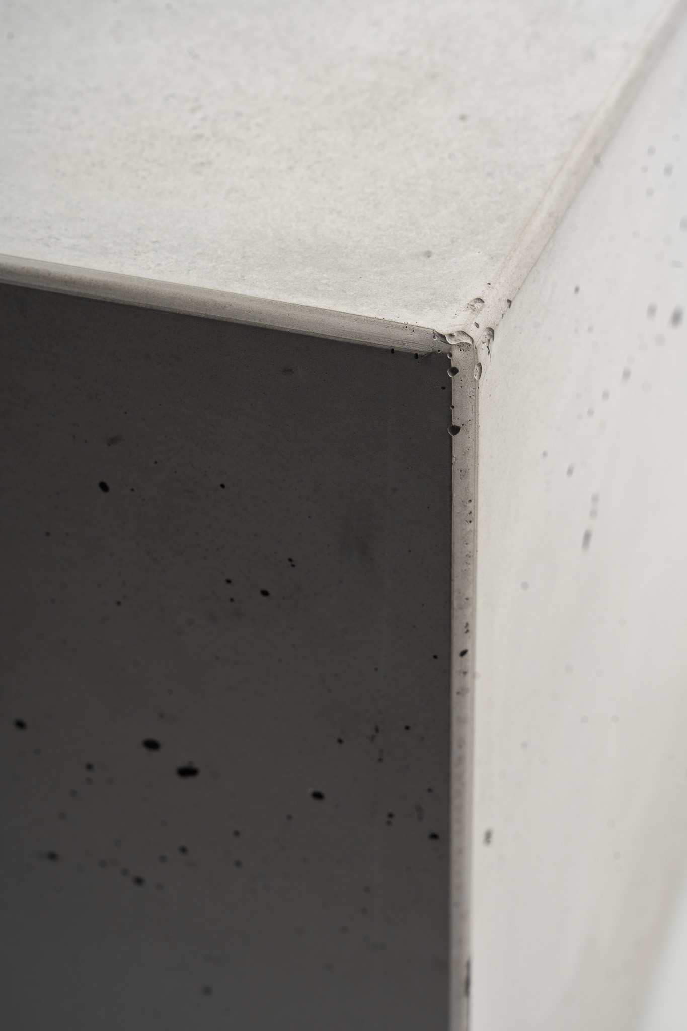 Senkrechte Kante und porige Seitenflächen des Betonwürfels SOLO, im Detail.