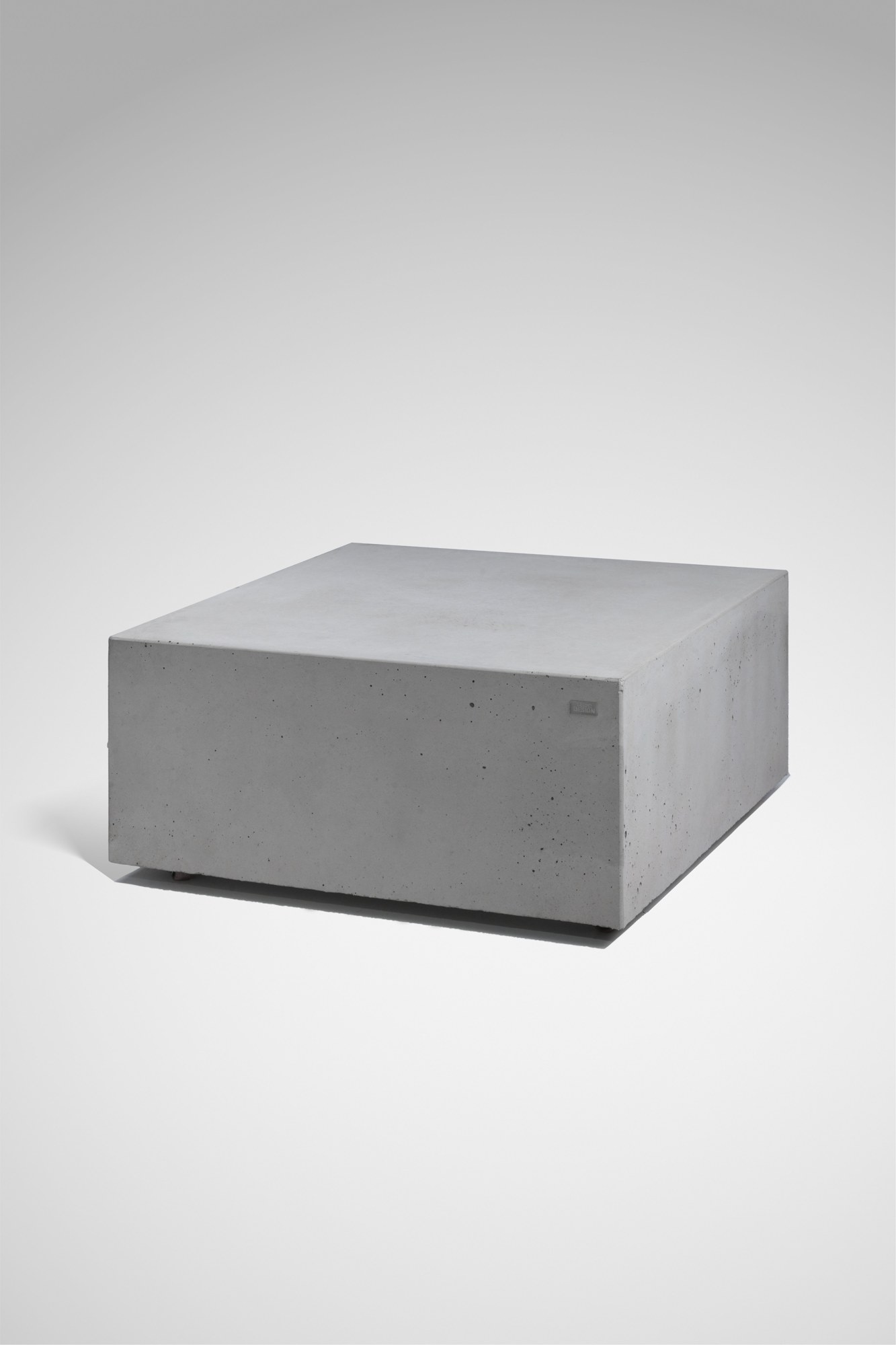 Quadratischer Couchtisch FLOAT aus Sichtbeton in geschlossener Blockform.