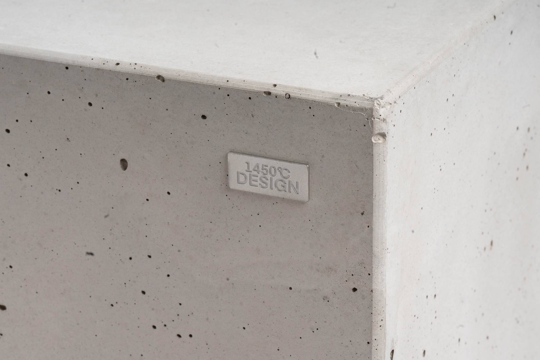 Porige Betonoberfläche des SOLO mit einer 1450°C Design Plakette.