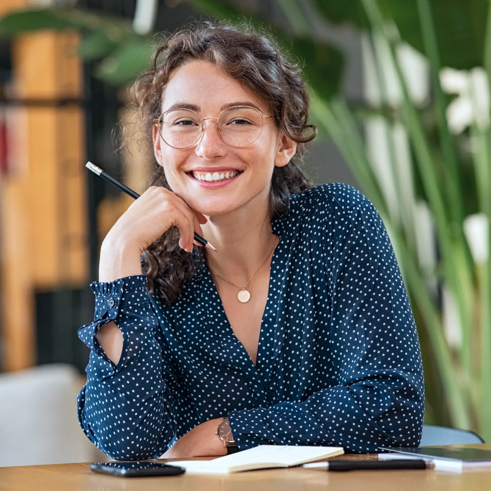 A woman sitting at a table with a pen in her hand.