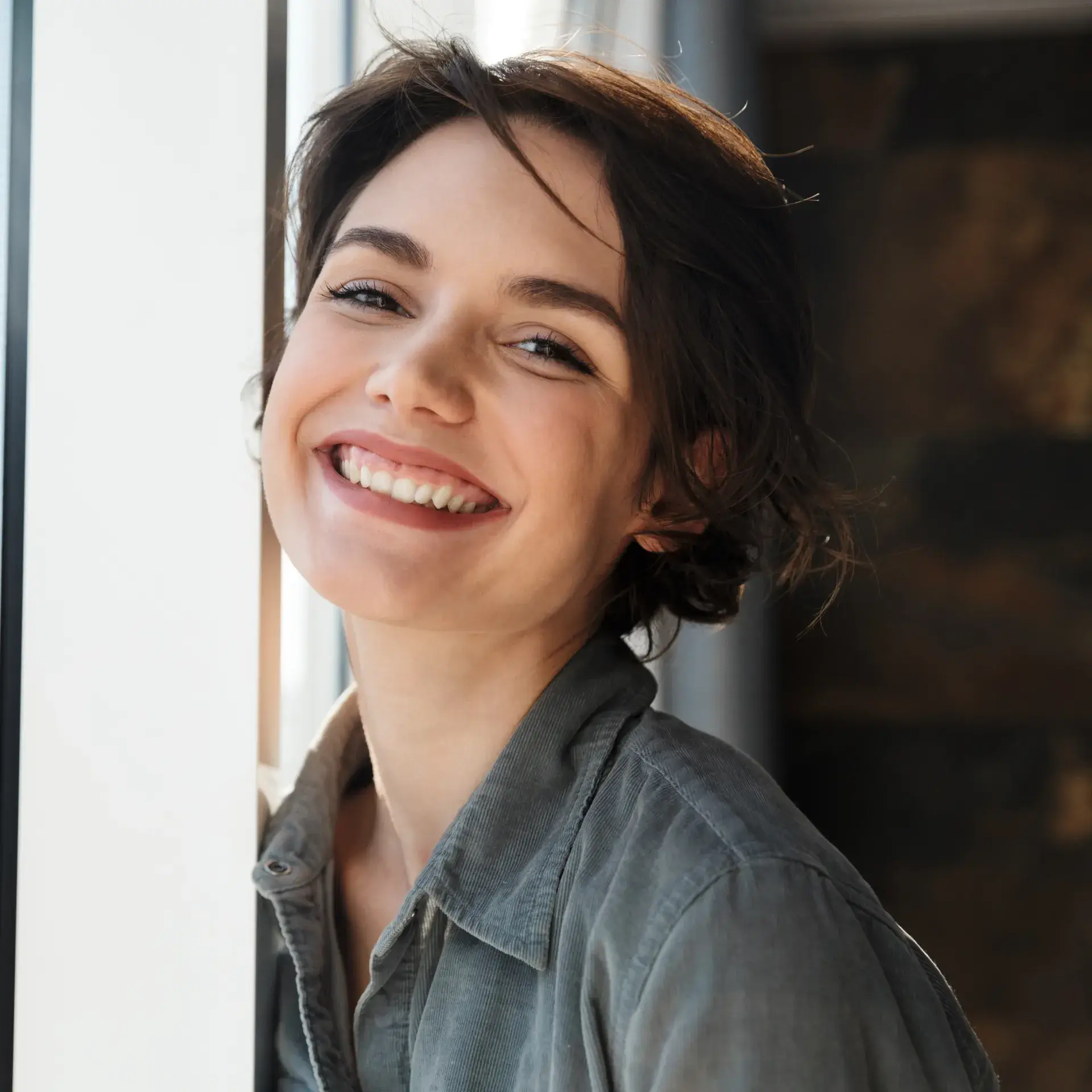 A woman smiling and leaning against a wall.
