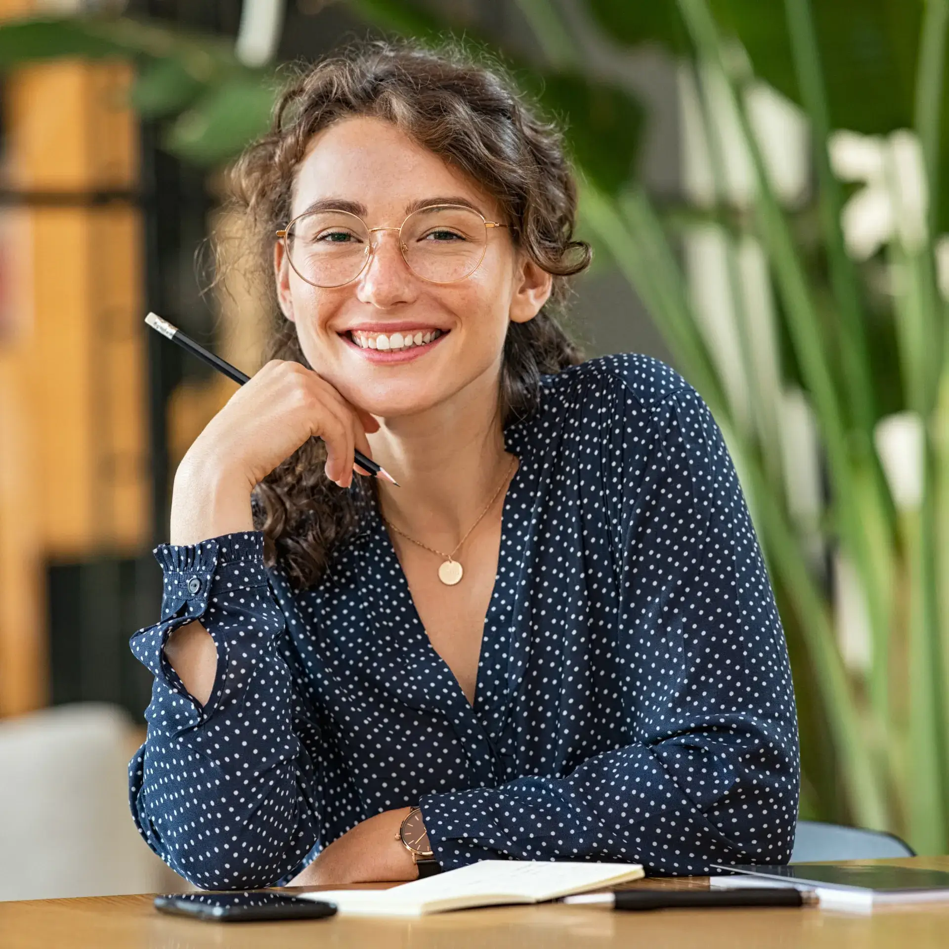 A woman sitting at a table with a pen in her hand.