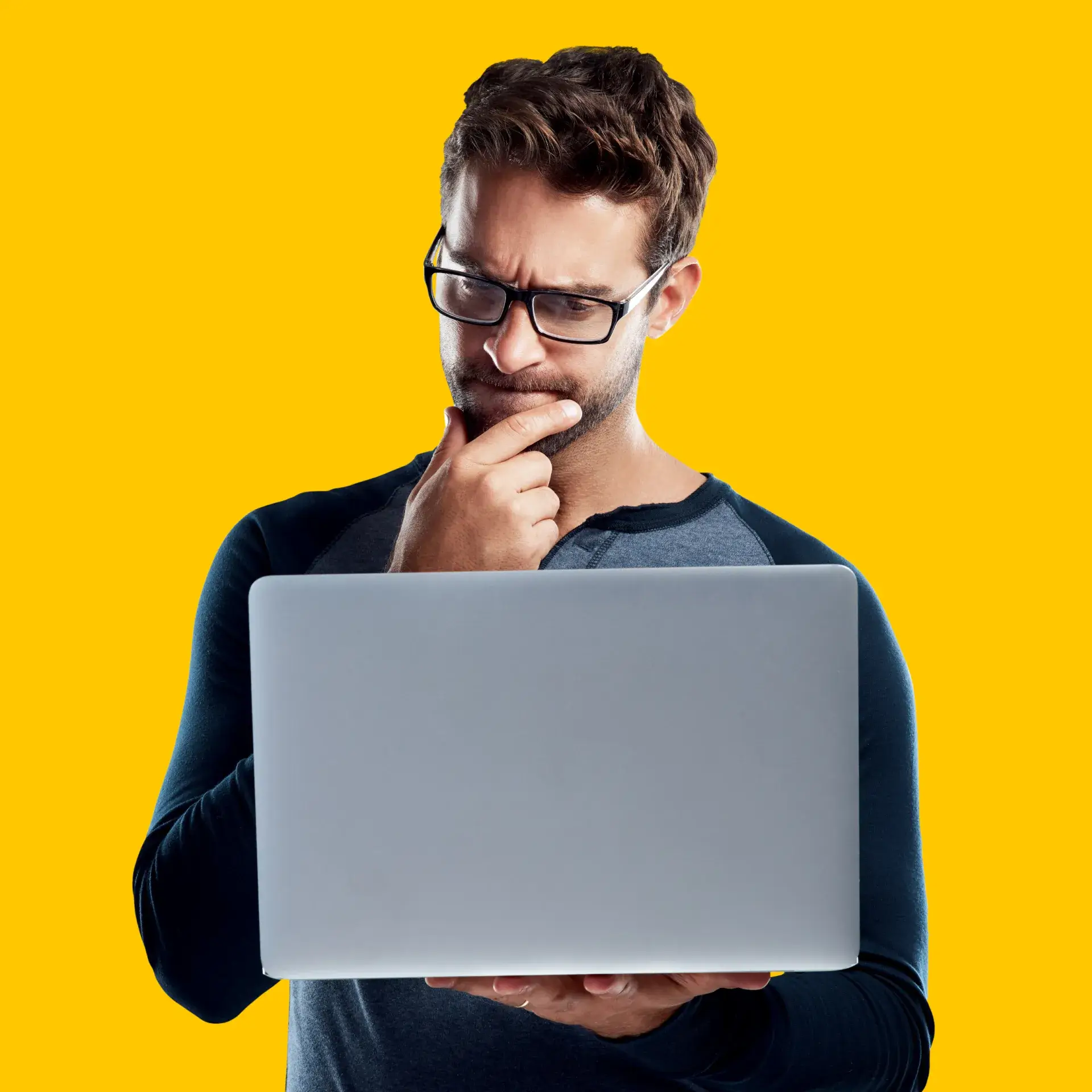 A man wearing glasses looking at a laptop.
