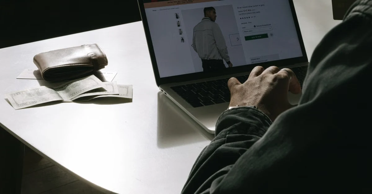Designer working on Shopify agencies product page layout on laptop with color palette and design notes on desk.