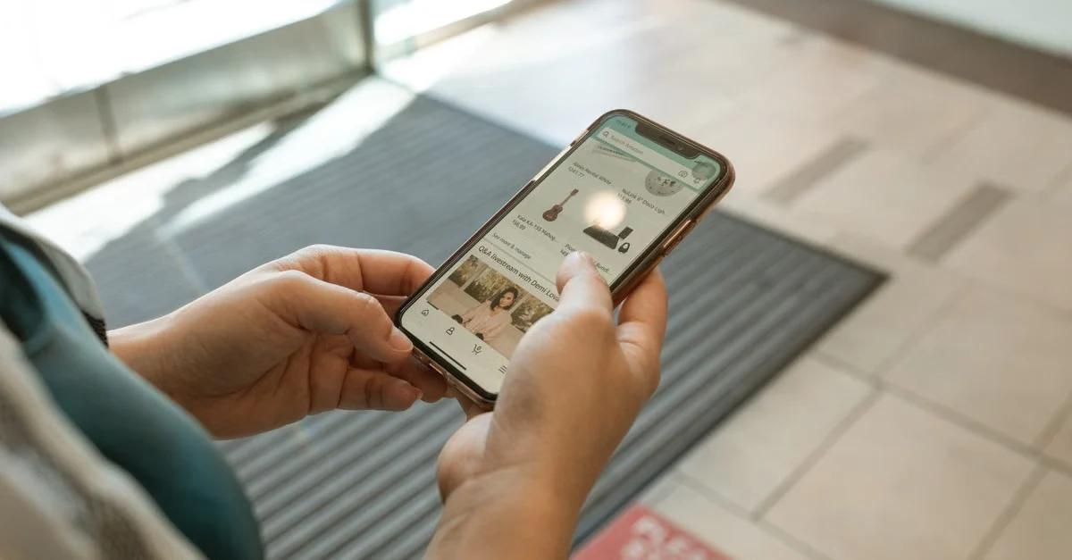 Person holding smartphone displaying ecommerce advertising product listings on mobile app in retail environment.