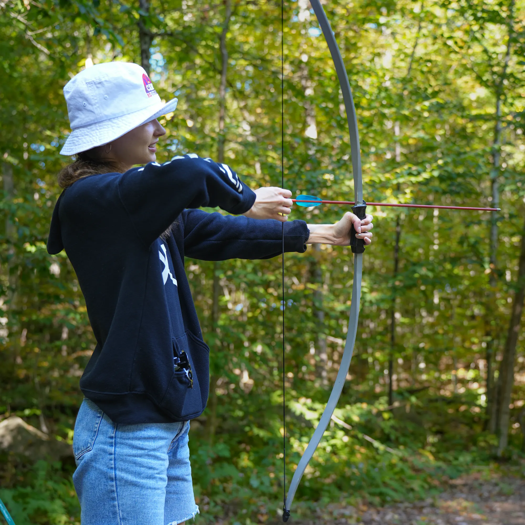 A woman trying archery at camp.