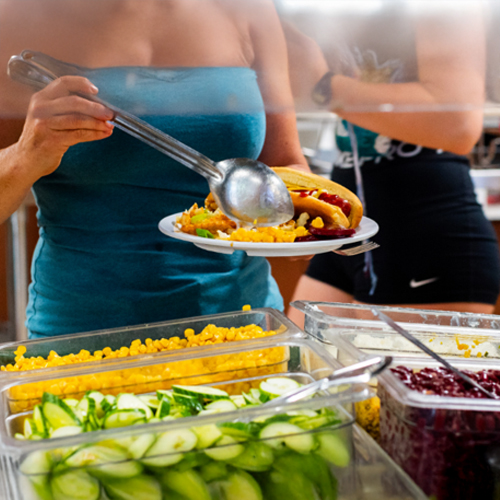 A woman serving herself food from a buffet table.