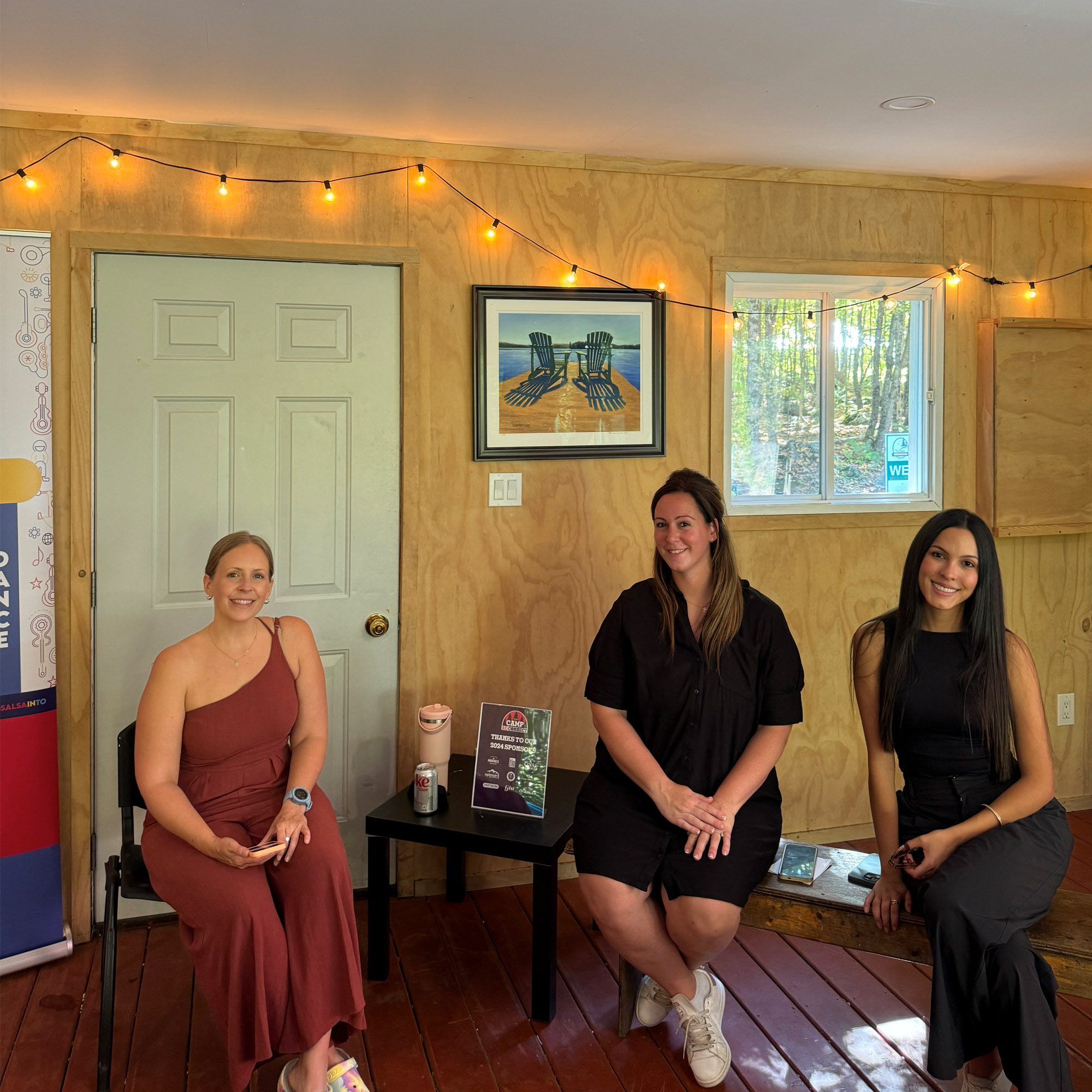 Three women, sitting and smiling.