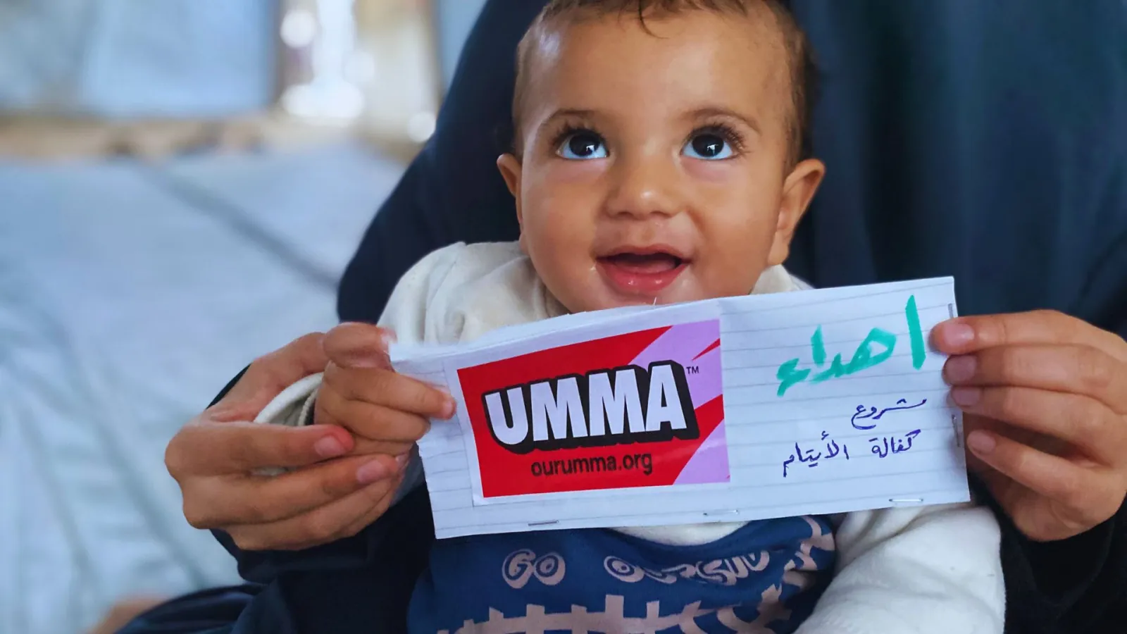 Smiling baby with Umma Foundation card