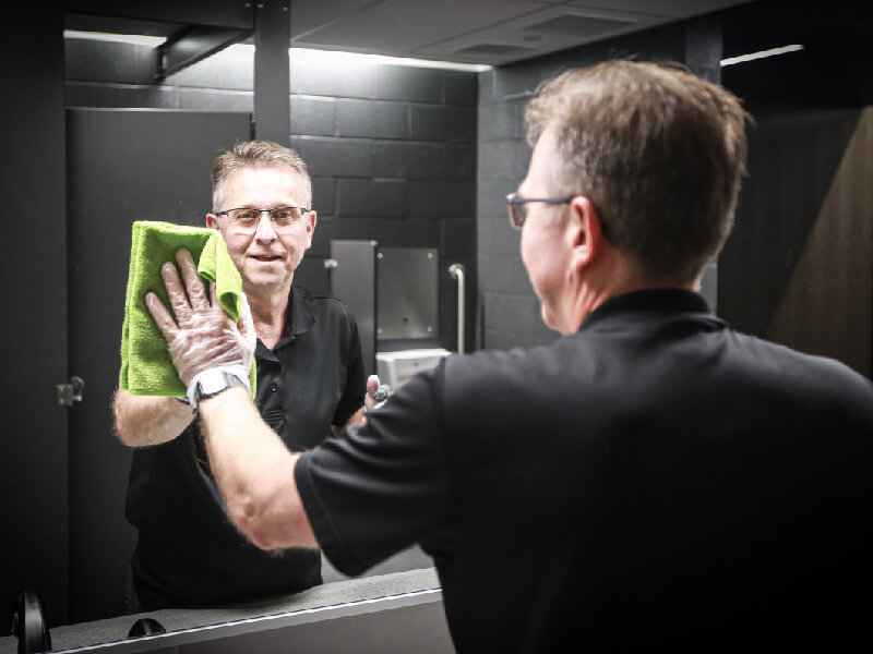 Employé souriant nettoie un miroir