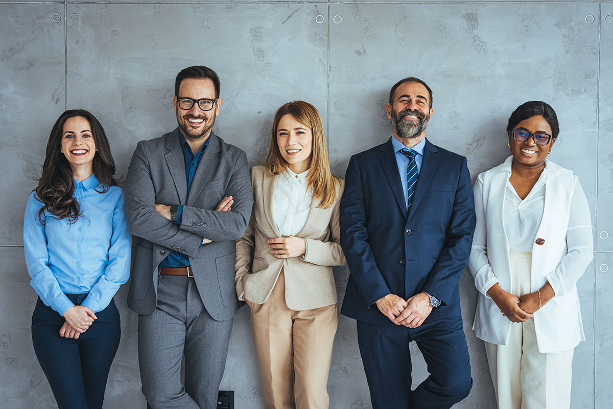 Group of smiling attorneys on a gray wall