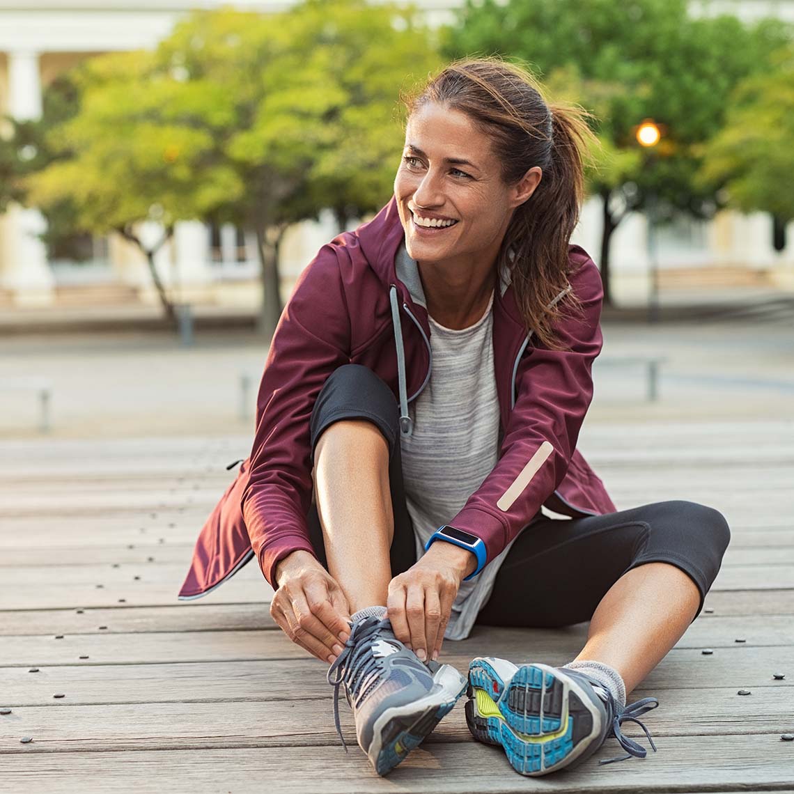 Fit smiling woman tying running shoes