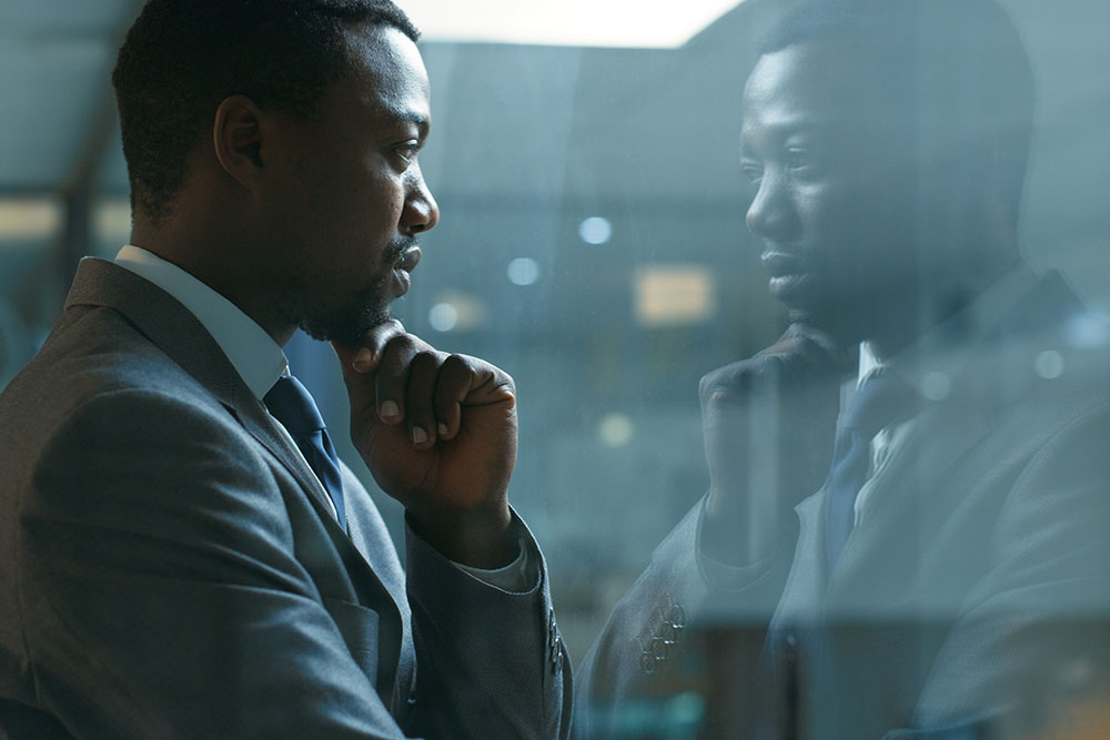 An attorney looking out the window and his reflection in the glass