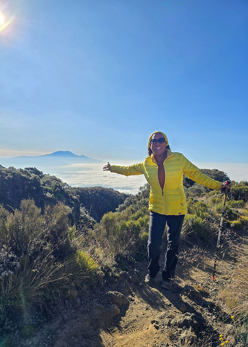 Kathy Richardson atop Mt. Meru, Mt. Kilimanjaro in the background