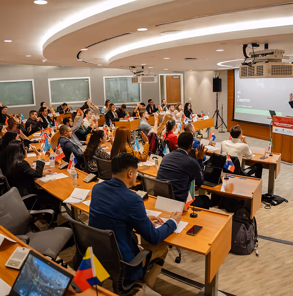 A group of people sitting at desks in front of a projector screen.