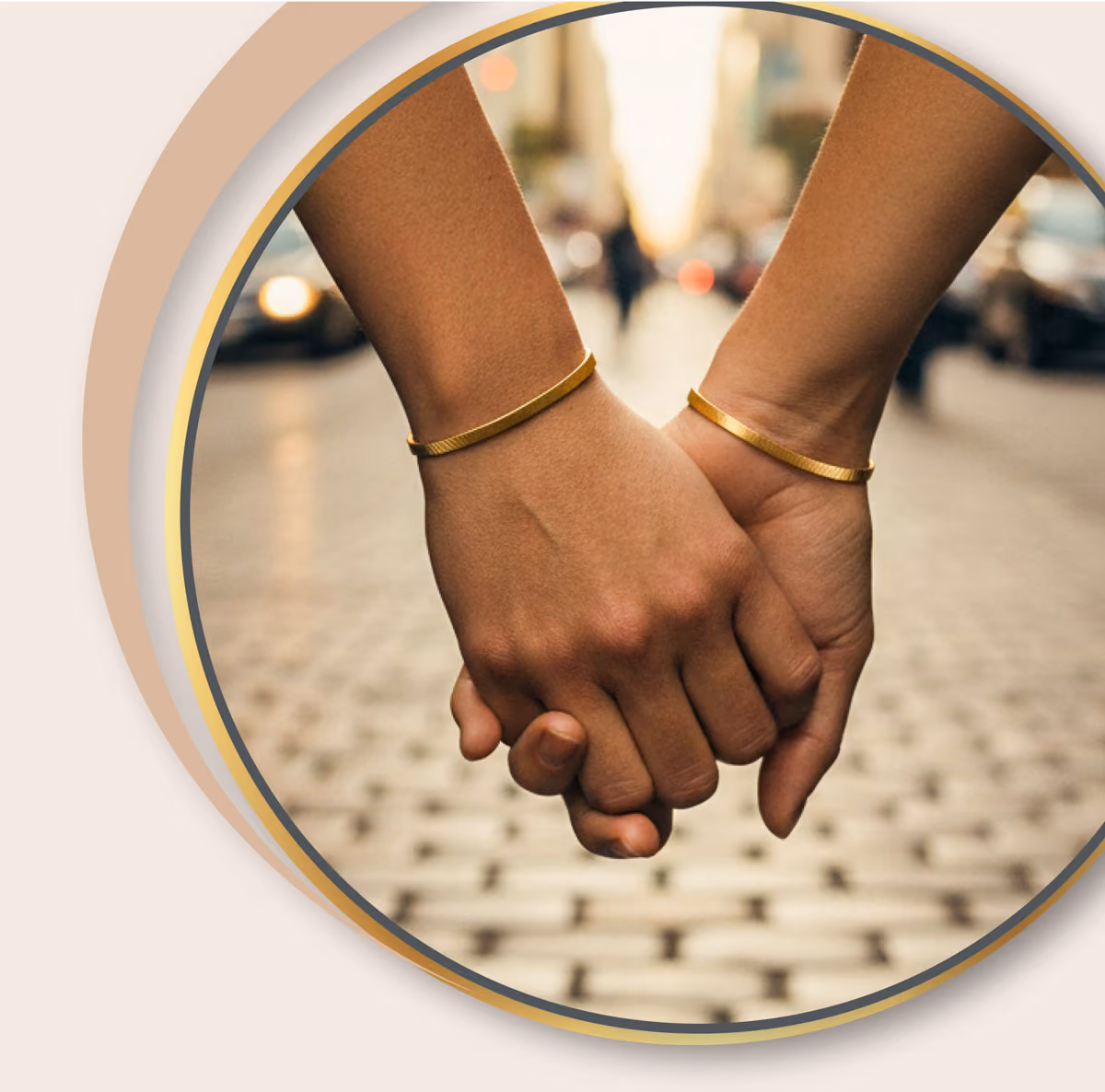 Zwei Hände mit goldenen Armbändern, die sich auf einer Straße in der Stadt halten, vor unscharfem Hintergrund.