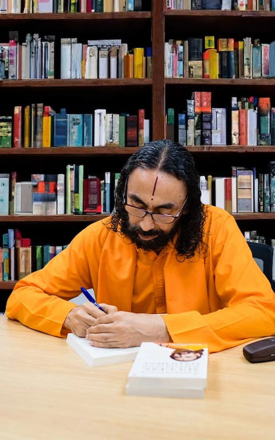 Swami Mukundananda signing a book in his library