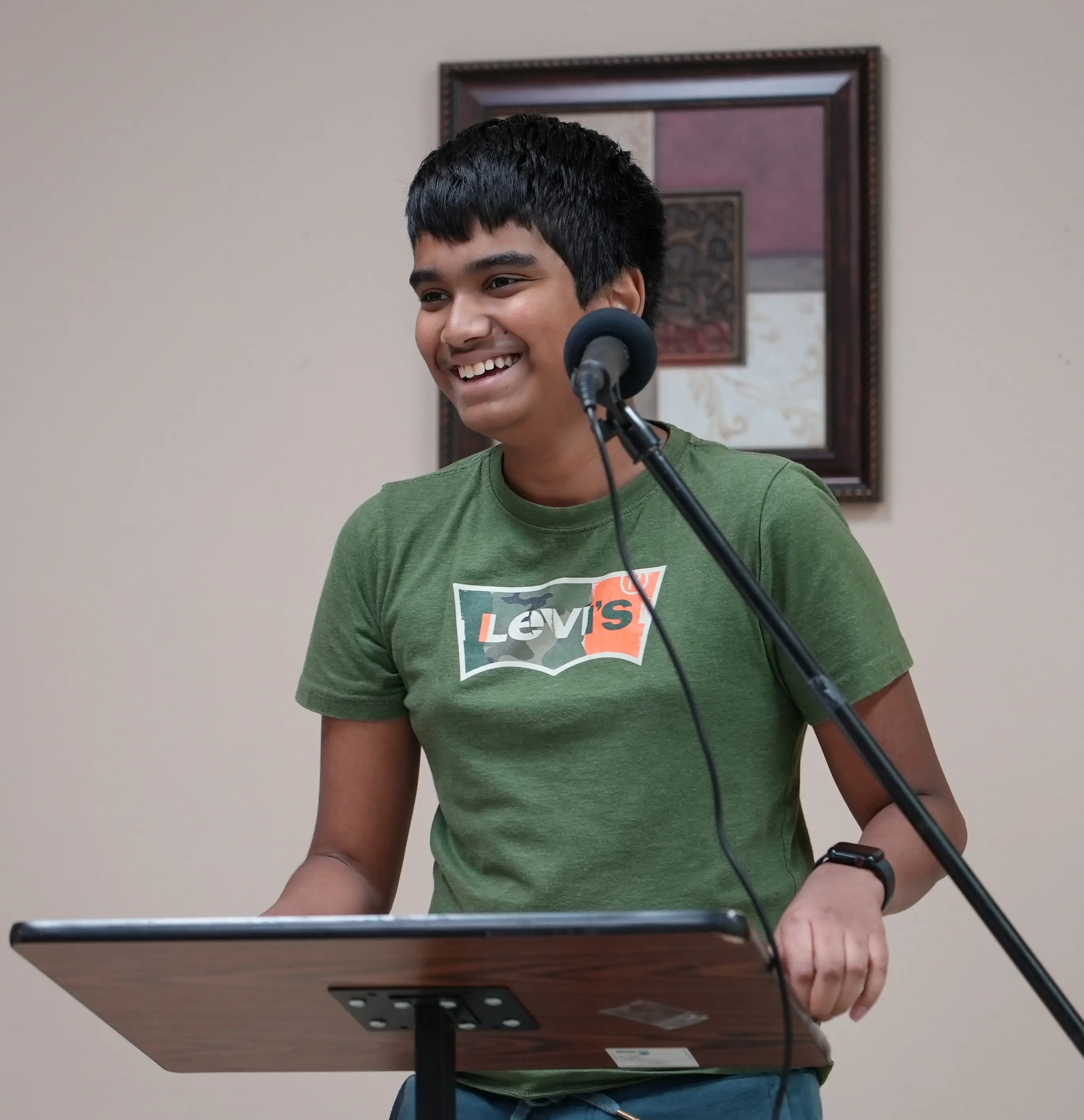 A young speaker smiling while presenting at the podium