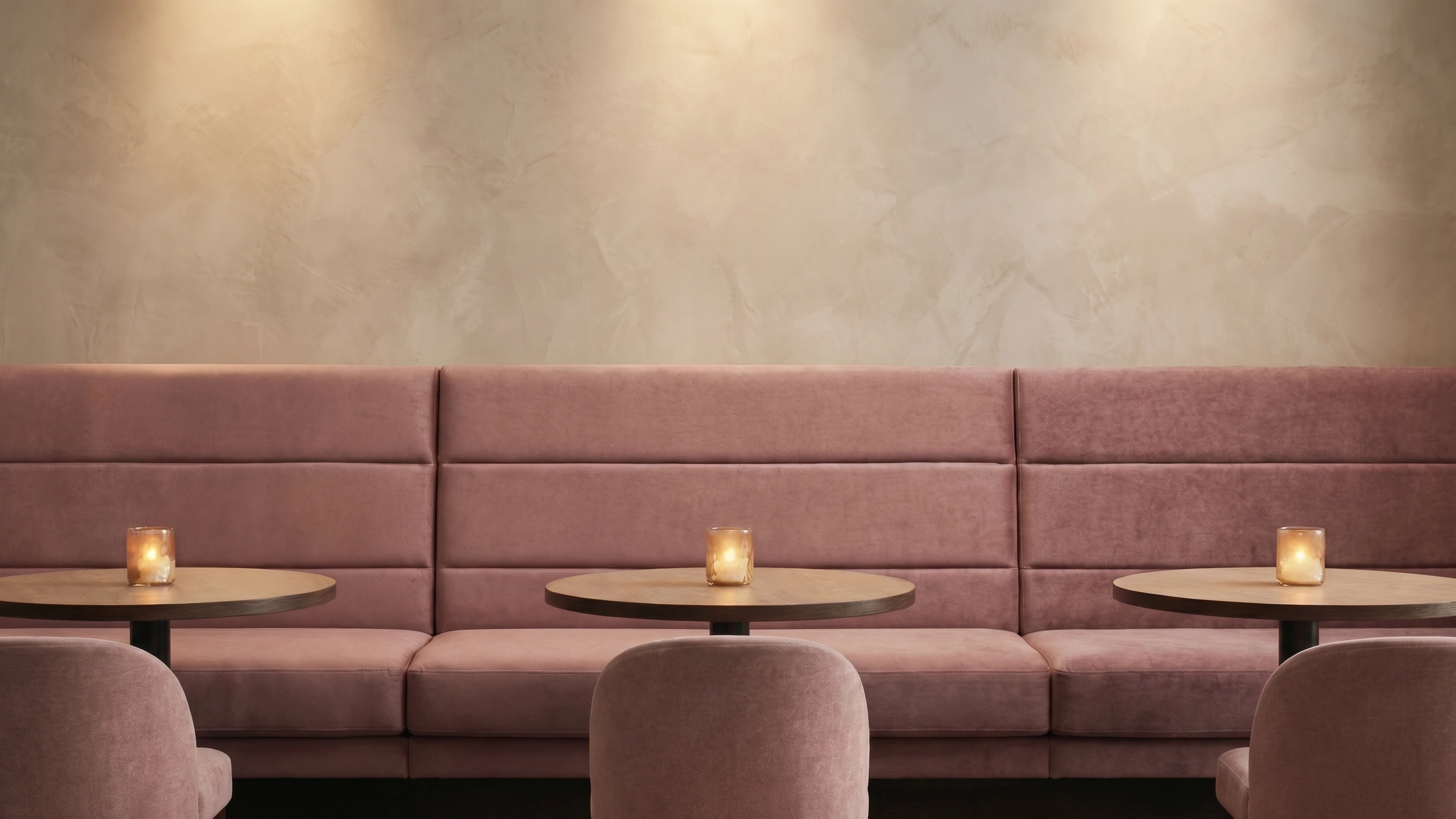 Dusty rose velvet banquette seating in a warm, softly lit hospitality interior