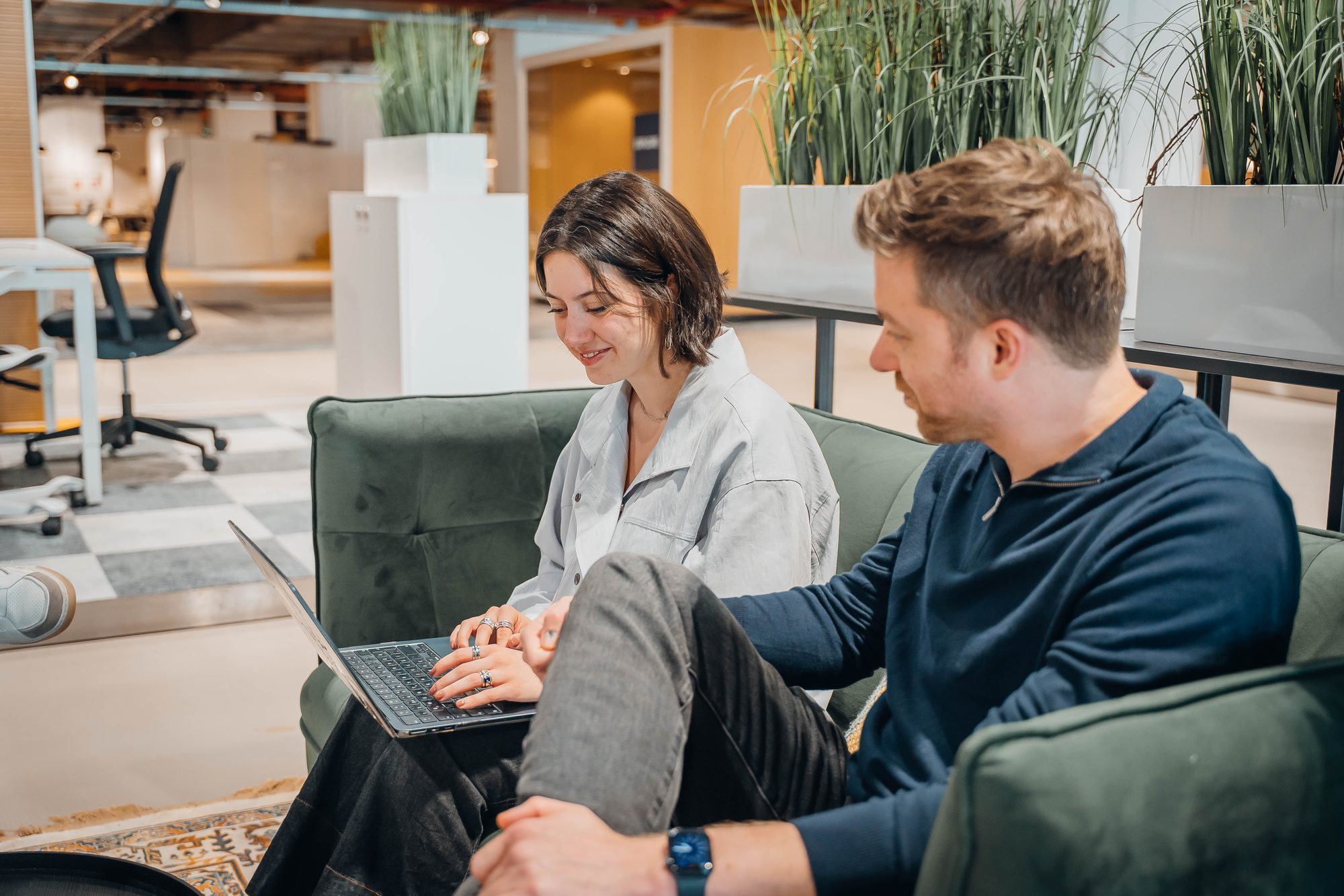 Een collega werkt een oefening door op een laptop terwijl een ander meekijkt