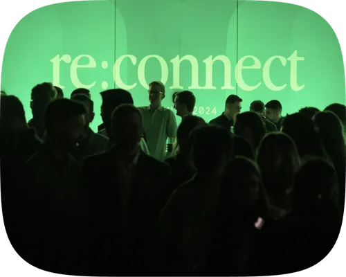 Crowd silhouettes at re:connect 2024 event with green-lit stage backdrop