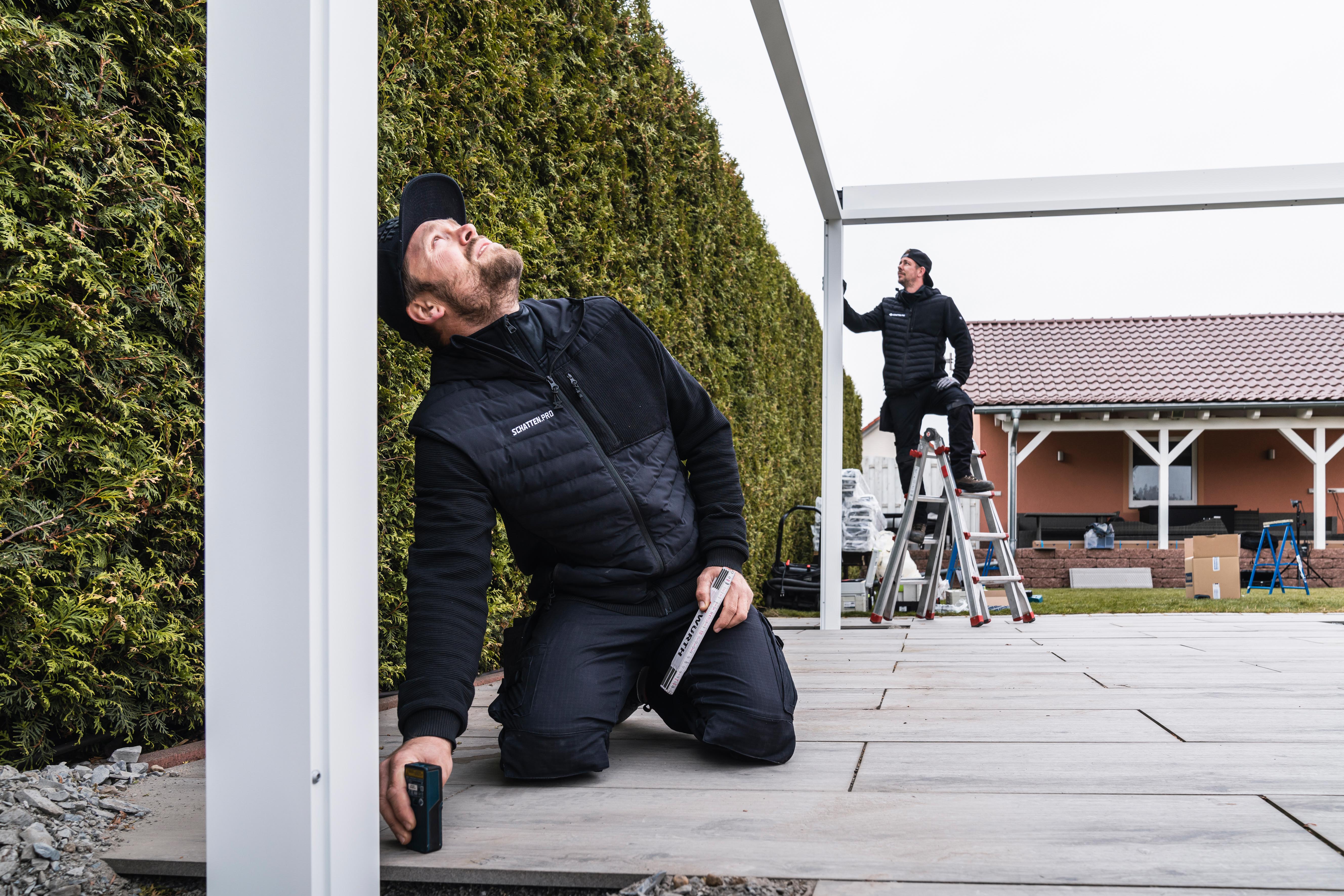 Monteur prüft eine Terrassenüberdachung bei der Montage