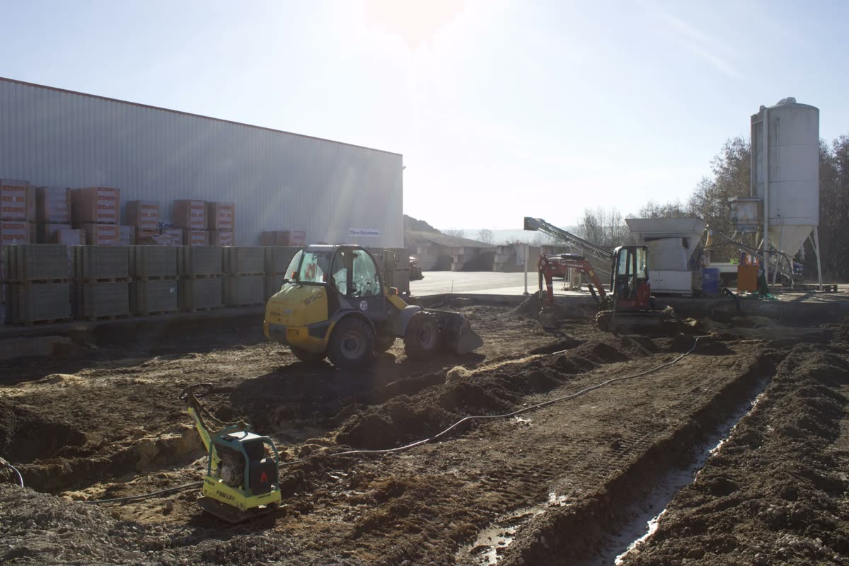 Baustelle mit Rüttelplatte und Erdarbeiten