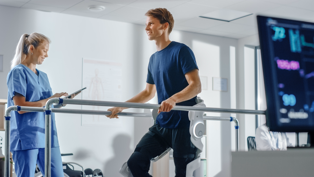 Physiotherapist supporting a patient during gait training on parallel bars