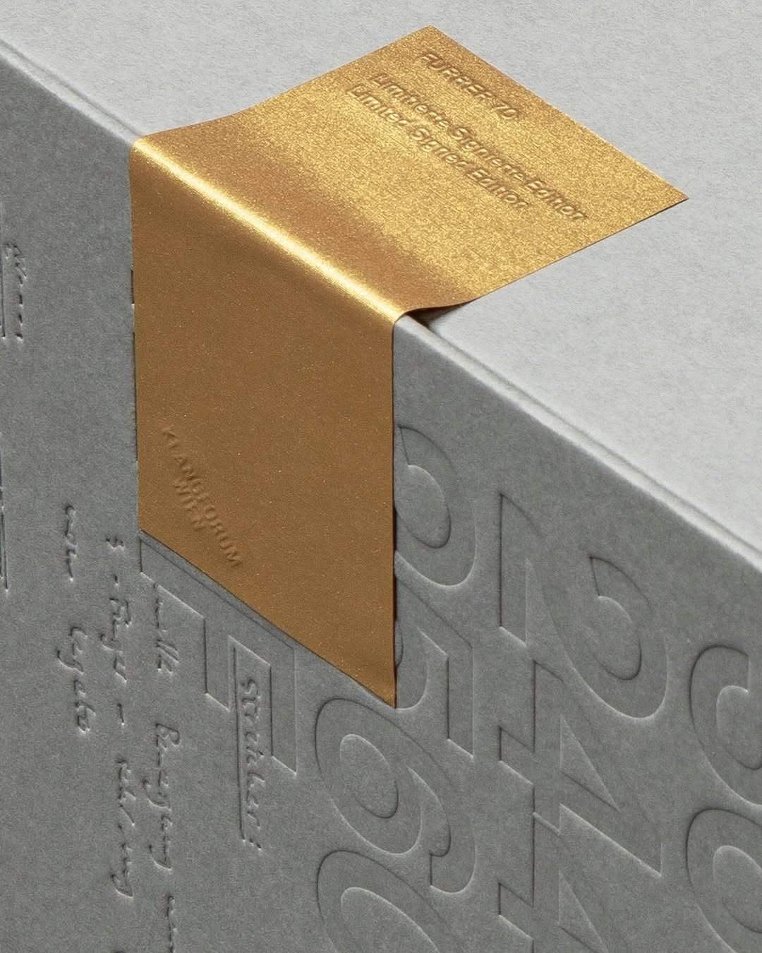 Detaliu de bandă metalică aurie aplicată pe o cutie rigidă premium.