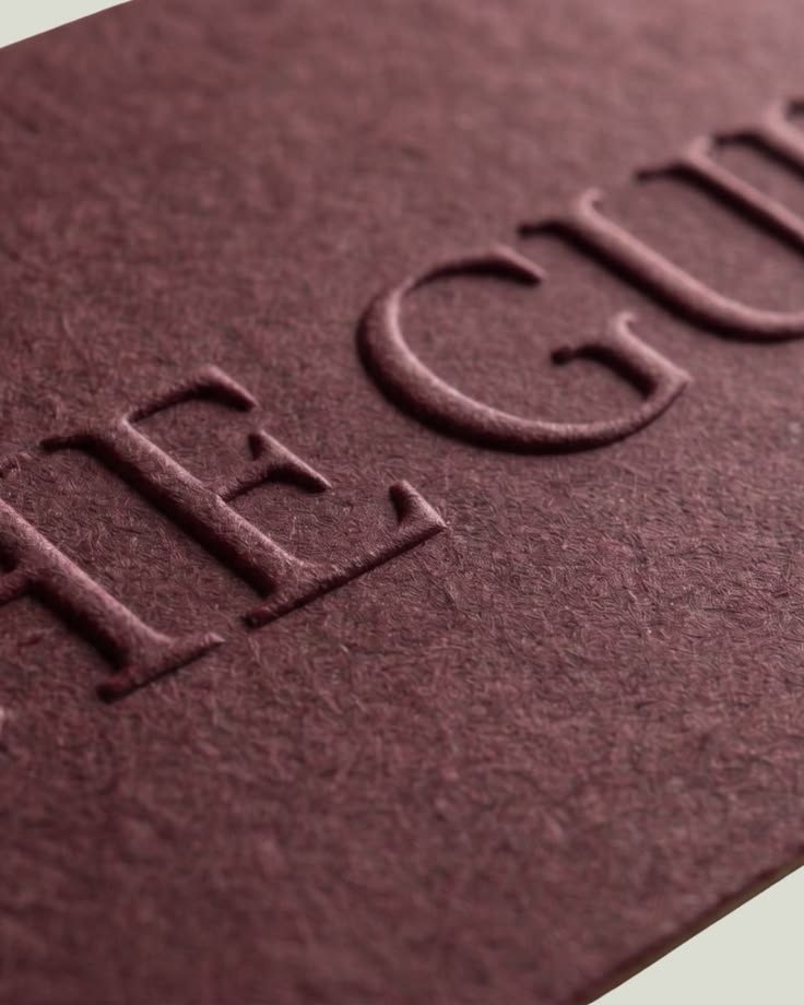 Detaliu de emboss pe carton burgundy pentru un ambalaj premium.