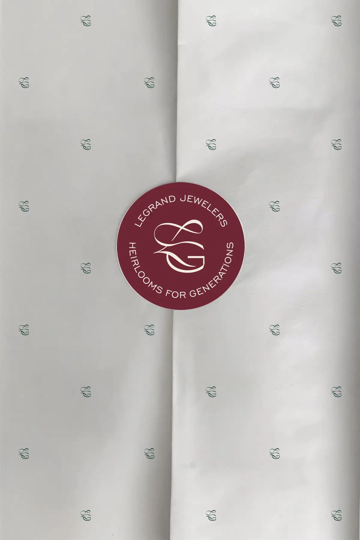 Pattern discret și sigiliu burgundy cu monograma GL pe hârtie ivory.