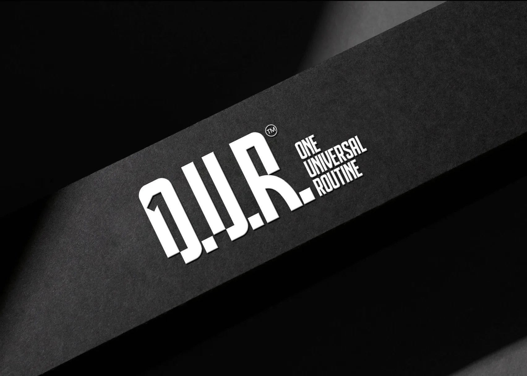 Logo-ul condensat O.U.R. One Universal Routine aplicat pe suport negru.