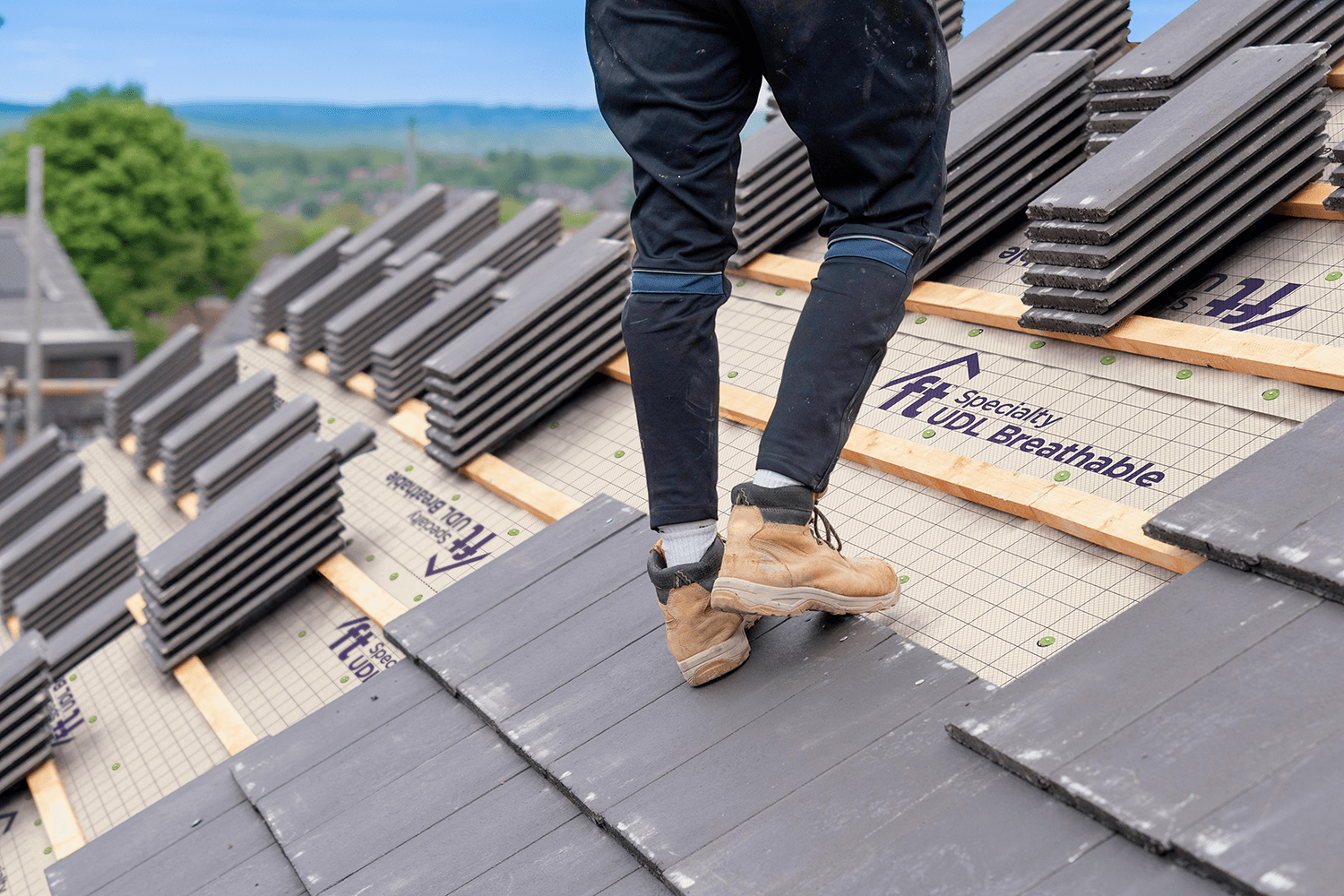 Roofer on Specialty UDL Breathable underlayment with slip-resistant GripSpot technology.