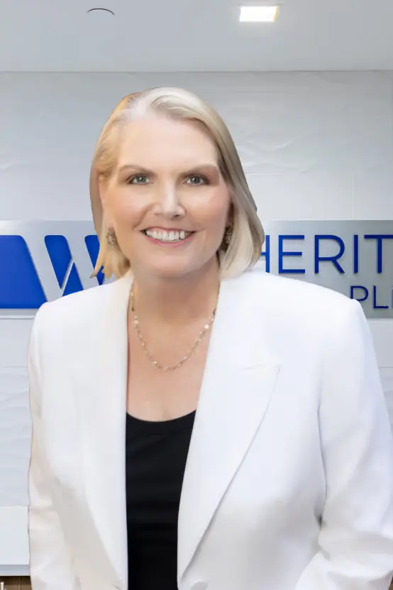 A professional, waist-up portrait of  Amy Witherite, wearing a white blazer over a black top and a delicate necklace. She stands in a modern office, with the blurred Witherite Law Group logo visible on the white wall behind her.