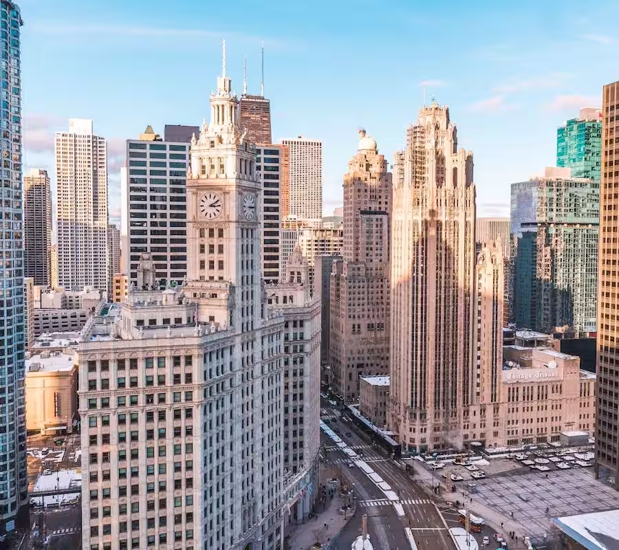 Chicago skyline view on a winter day, featuring the prominent Wrigley Building (with clock tower) and the Tribune Tower, surrounded by other downtown skyscrapers.