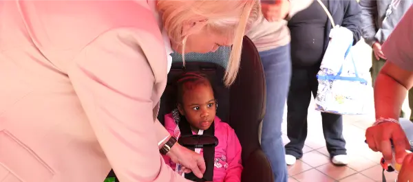 Amy Witherite adjusts the harness of a child seated in a car seat or strolly seat during a safety check event.