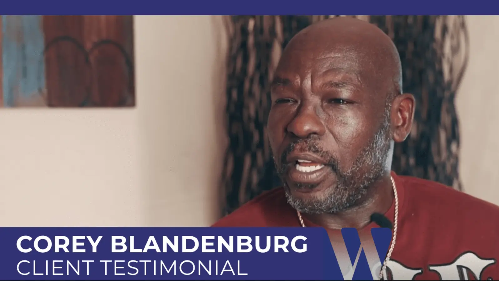 Corey Blandenburg speaking during his client testimonial video, wearing a distinctive red shirt.