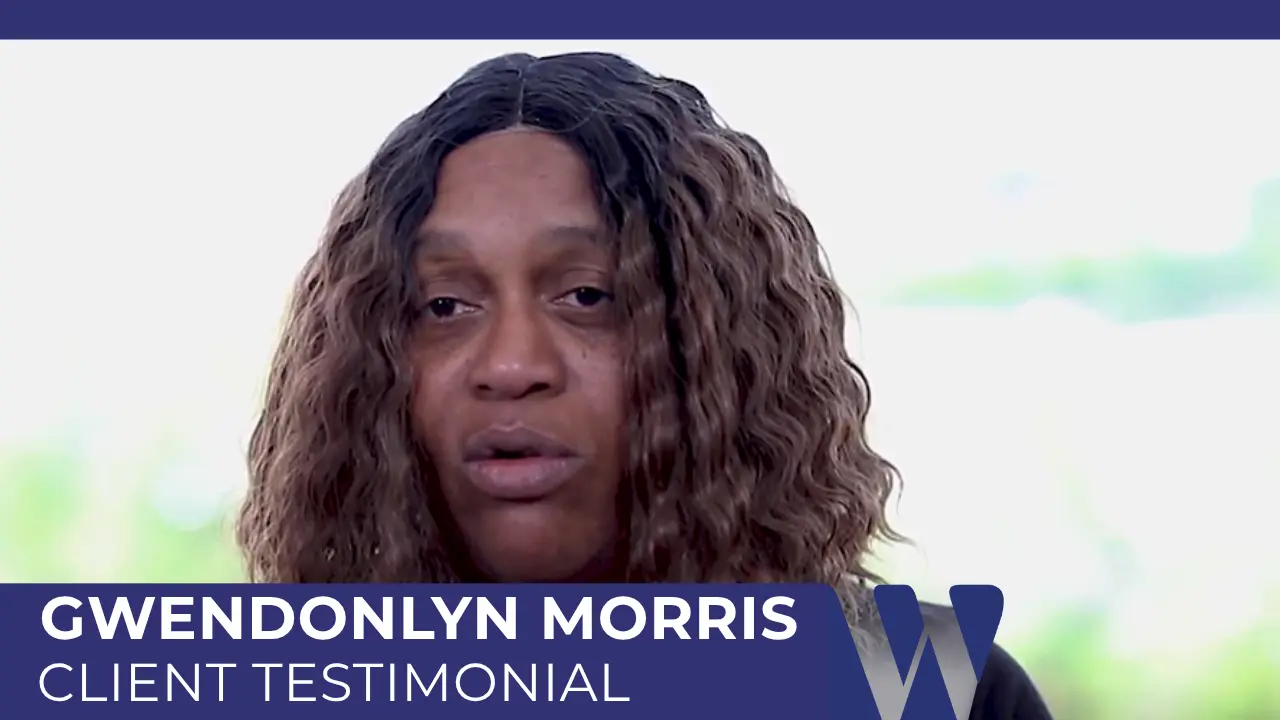 Gwendolyn Morris in a video screenshot, speaking directly to the camera. She is a Black woman with long, dark, wavy hair and is wearing a dark, high-collared garment.