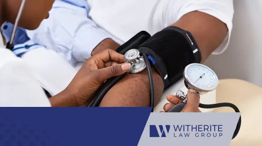 A close-up shot of a healthcare worker checking the blood pressure of a patient's arm using a manual blood pressure cuff and a stethoscope. The Witherite Law Group logo is overlaid in the lower right corner.