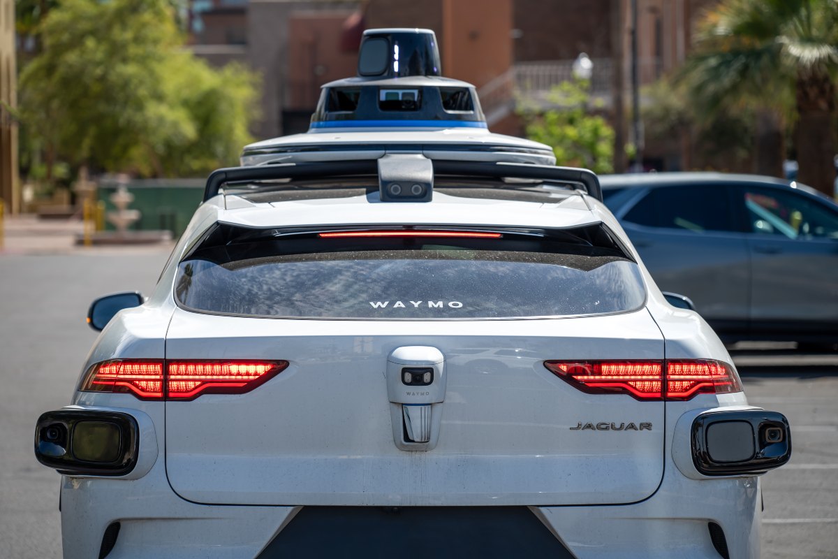 Rear view of a self-driving car with roof-mounted sensors on a city street