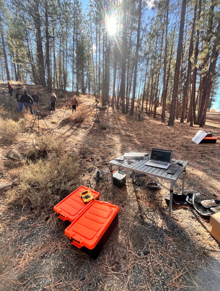 Outdoor motion capture setup for biomechanics research at Oregon State University, showing laptop, cameras, and field equipment positioned along a forested trail.