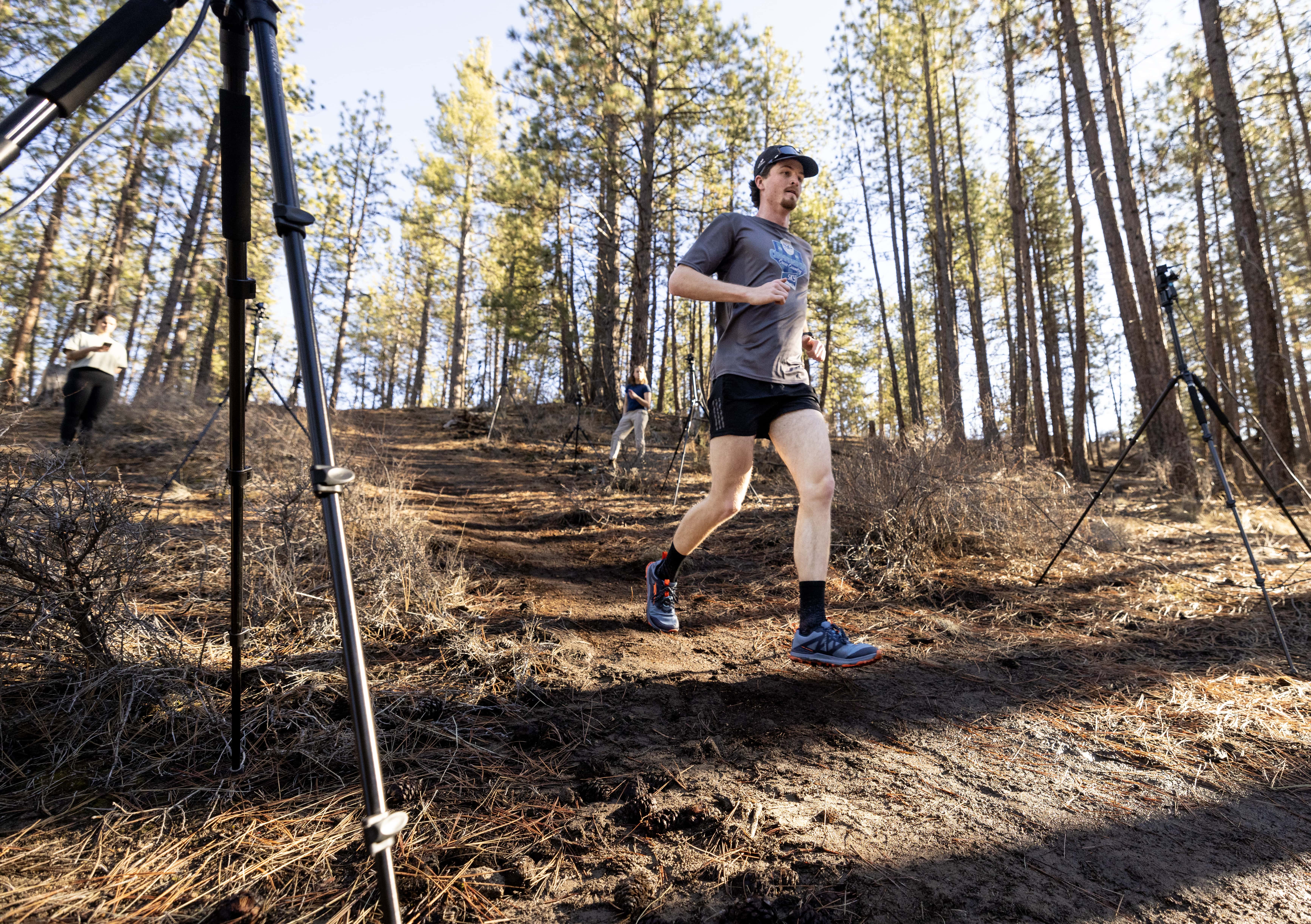 Male trail runner descending a forested trail during Oregon State University's markerless motion capture study using Theia3D.