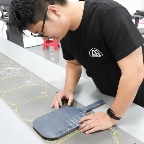 Mozkuib team checking a carbon fiber pickleball paddle surface during production inspection